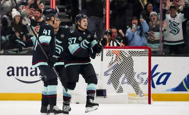 Seattle Kraken center Yanni Gourde (37) celebrates his goal against the Utah Hockey Club with defenseman Ryker Evans (41) and center Jaden Schwartz, back, during the first period of an NHL hockey game Monday, Dec. 30, 2024, in Seattle. (AP Photo/Lindsey Wasson)