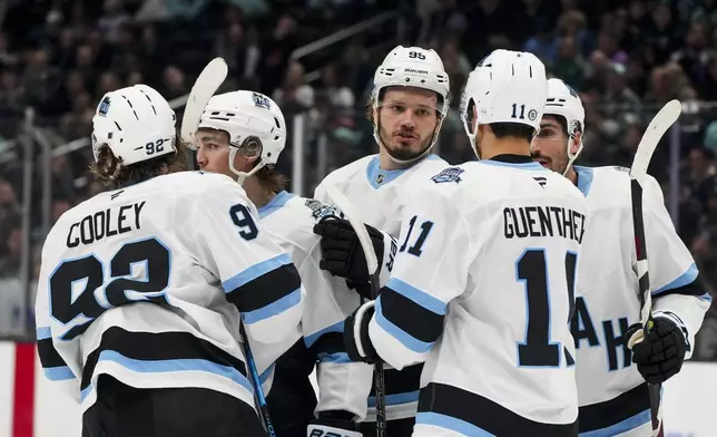 Utah Hockey Club center Logan Cooley (92) celebrates his goal against the Seattle Kraken with teammates, including defenseman Mikhail Sergachev (98)ref10 and right wing Dylan Guenther (11) during the first period of an NHL hockey game Monday, Dec. 30, 2024, in Seattle. (AP Photo/Lindsey Wasson)