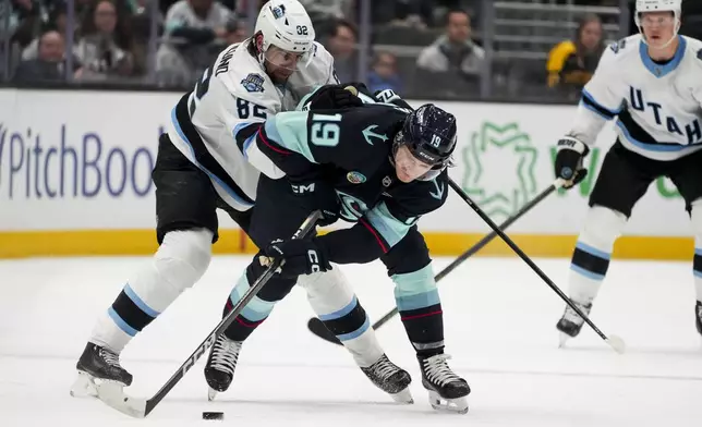 Utah Hockey Club center Kevin Stenlund (82) and Seattle Kraken left wing Jared McCann (19) vie for the puck during the first period of an NHL hockey game Monday, Dec. 30, 2024, in Seattle. (AP Photo/Lindsey Wasson)