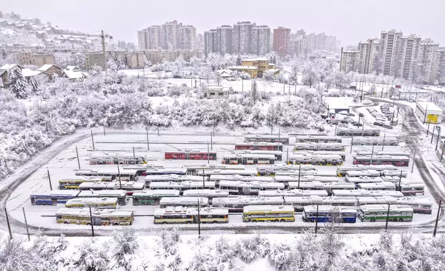 An aerial view of parked trolley buses during heavy snowfall in Sarajevo, Bosnia, Tuesday, Dec. 24, 2024. (AP Photo/Armin Durgut)