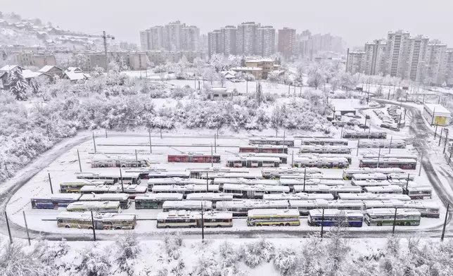 An aerial view of parked trolley buses during heavy snowfall in Sarajevo, Bosnia, Tuesday, Dec. 24, 2024. (AP Photo/Armin Durgut)