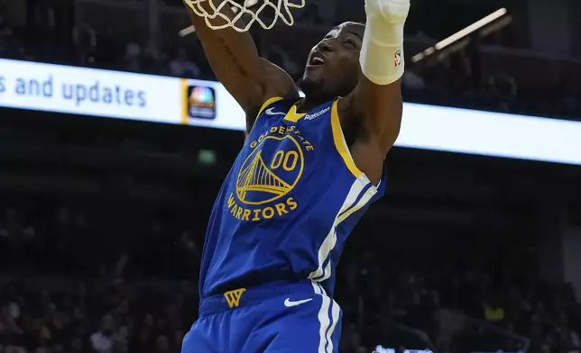 Golden State Warriors forward Jonathan Kuminga, left, dunks next to Phoenix Suns forward Kevin Durant during the first half of an NBA basketball game Saturday, Dec. 28, 2024, in San Francisco. (AP Photo/Godofredo A. Vásquez)