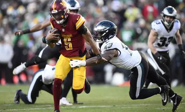 Washington Commanders quarterback Jayden Daniels (5) breaks away from Philadelphia Eagles linebacker Nakobe Dean (17) and runs with the ball during the second half of an NFL football game, Sunday, Dec. 22, 2024, in Landover, Md. (AP Photo/Nick Wass)