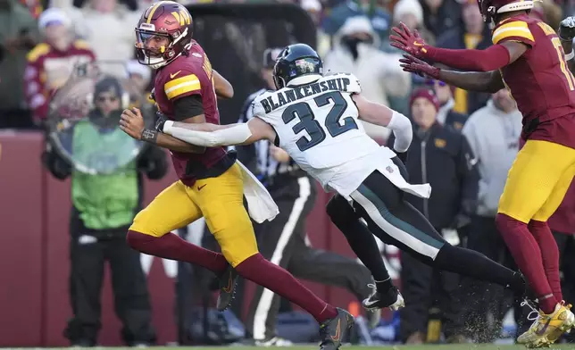 Washington Commanders quarterback Jayden Daniels (5) avoids a tackle by Philadelphia Eagles safety Reed Blankenship (32) during the second half of an NFL football game, Sunday, Dec. 22, 2024, in Landover, Md. (AP Photo/Stephanie Scarbrough)