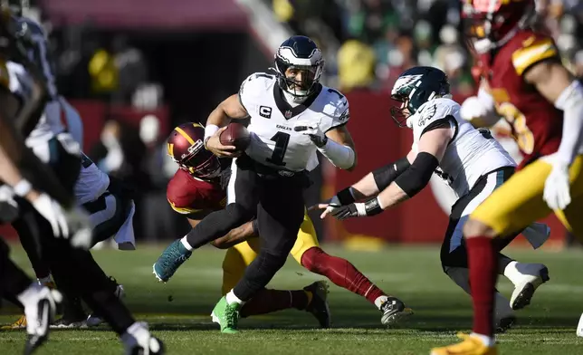 Philadelphia Eagles quarterback Jalen Hurts (1) scrambles as he carries the ball during the first half of an NFL football game against the Washington Commanders, Sunday, Dec. 22, 2024, in Landover, Md. (AP Photo/Nick Wass)