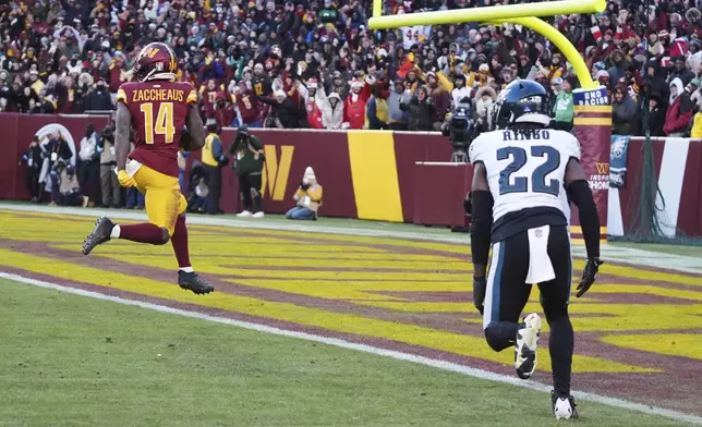 Washington Commanders wide receiver Olamide Zaccheaus (14) scores a touchdown against Philadelphia Eagles cornerback Kelee Ringo (22) during the second half of an NFL football game, Sunday, Dec. 22, 2024, in Landover, Md. (AP Photo/Stephanie Scarbrough)