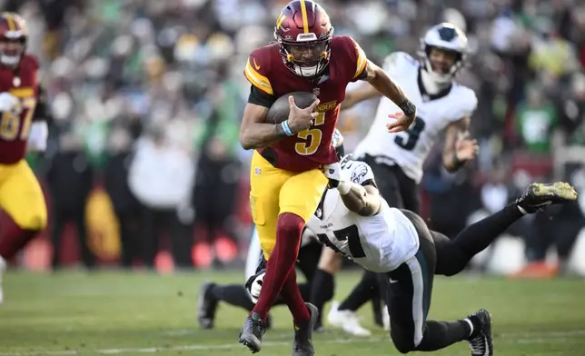 Washington Commanders quarterback Jayden Daniels (5) breaks away from Philadelphia Eagles linebacker Nakobe Dean (17) and runs with the ball during the second half of an NFL football game, Sunday, Dec. 22, 2024, in Landover, Md. (AP Photo/Nick Wass)