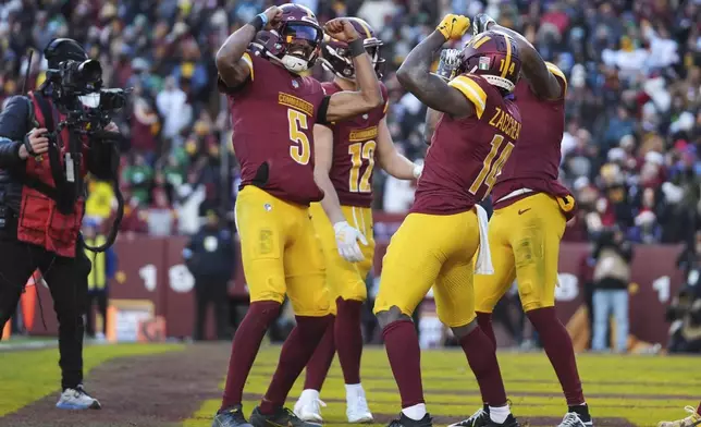 Washington Commanders wide receiver Olamide Zaccheaus (14) celebrating his touchdown with Washington Commanders quarterback Jayden Daniels (5) and others during the second half of an NFL football game against the Philadelphia Eagles, Sunday, Dec. 22, 2024, in Landover, Md. (AP Photo/Stephanie Scarbrough)