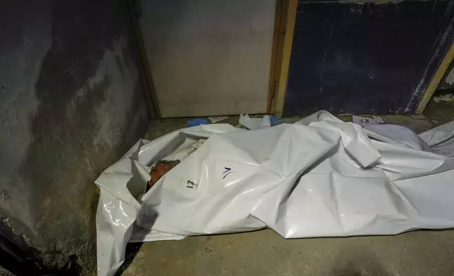 EDS NOTE: GRAPHIC CONTENT - A body wrapped in a plastic bag lies on the floor of the morgue at Al-Mojtahed hospital in Damascus, Syria, on Wednesday, Dec. 11, 2024. Syrians are flocking to morgues, hoping to identify their slain loved ones who may have been imprisoned under the rule of President Bashar Assad, whose government collapsed over the weekend. (AP Photo/Hussein Malla)