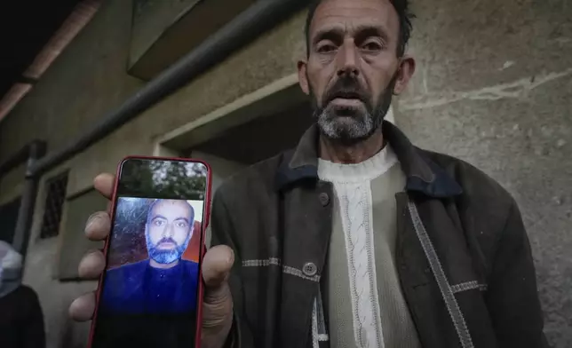 Abou Ahmad holds a picture of his son, who went missing while imprisoned by the late Syrian government, as he searches for his body at the Al-Mojtahed hospital morgue in Damascus, Syria, on Wednesday, Dec. 11, 2024. Many are flocking to morgues, hoping to identify loved ones who have been killed or were imprisoned under the rule of President Bashar Assad, whose government collapsed over the weekend.(AP Photo/Hussein Malla)