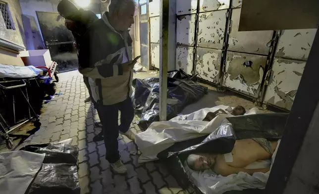 EDS NOTE: GRAPHIC CONTENT - Syrians examine bodies wrapped in plastic bags while searching for missing people at the morgue of the Al-Mojtahed hospital in Damascus, Syria, on Wednesday, Dec. 11, 2024. Many are flocking to morgues, hoping to identify loved ones who have been killed or were imprisoned under the rule of President Bashar Assad, whose government collapsed over the weekend. (AP Photo/Hussein Malla)