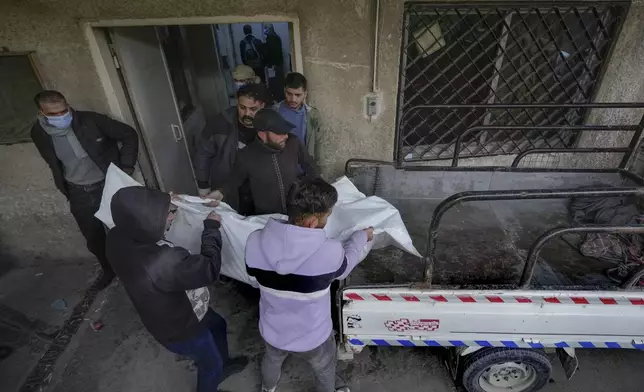 Syrian citizens carry the body of Sami Chouaib, 34, who had been a prisoner of Syrian security forces, after his body was found at the Al-Mojtahed Hospital morgue in Damascus, Syria, on Wednesday, Dec. 11, 2024. Many people are flocking to morgues, hoping to identify loved ones who were either killed or imprisoned under President Bashar Assad's government, which collapsed over the weekend. (AP Photo/Hussein Malla)