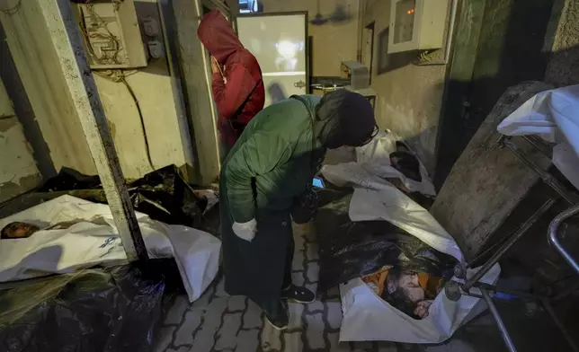 EDS NOTE: GRAPHIC CONTENT - Syrians examine bodies wrapped in plastic bags while searching for missing people at the morgue of Al-Mojtahed hospital in Damascus, Syria, on Wednesday, Dec. 11, 2024. Many are flocking to morgues, hoping to identify loved ones who have been killed or were imprisoned under the rule of President Bashar Assad, whose government collapsed over the weekend. (AP Photo/Hussein Malla)