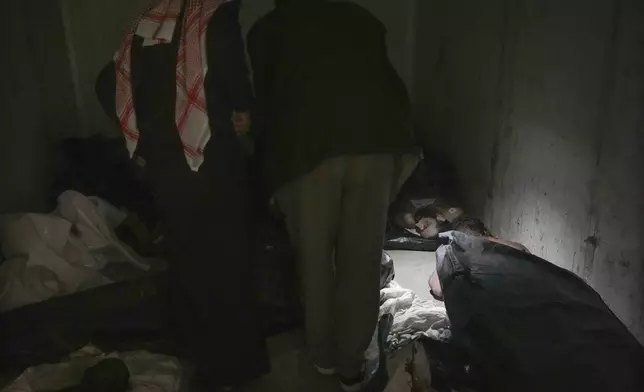 EDS NOTE: GRAPHIC CONTENT - Men examine bodies as they search for missing people at the morgue of Al-Mojtahed Hospital in Damascus, Syria, on Wednesday, Dec. 11, 2024. Many are flocking to morgues, hoping to identify loved ones who were either killed or imprisoned under President Bashar Assad's government, which collapsed over the weekend. (AP Photo/Hussein Malla)