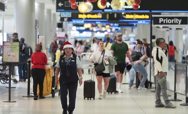 An American Airlines employee wearing a Santa Claus hat walks through the American terminal at Miami International Airport, on Christmas Eve, Tuesday, Dec. 24, 2024, in Miami. (AP Photo/Rebecca Blackwell)