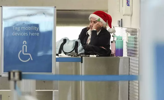 An American Airlines employee wearing a Santa Claus hat looks toward quiet check-in counters in the American terminal at Miami International Airport, on Christmas Eve, Tuesday, Dec. 24, 2024, in Miami. (AP Photo/Rebecca Blackwell)