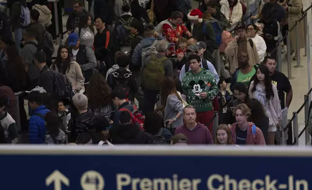 Travelers wait in line for security checks at the Los Angeles International Airport in Los Angeles, Tuesday, Dec. 24, 2024. (AP Photo/Jae C. Hong)