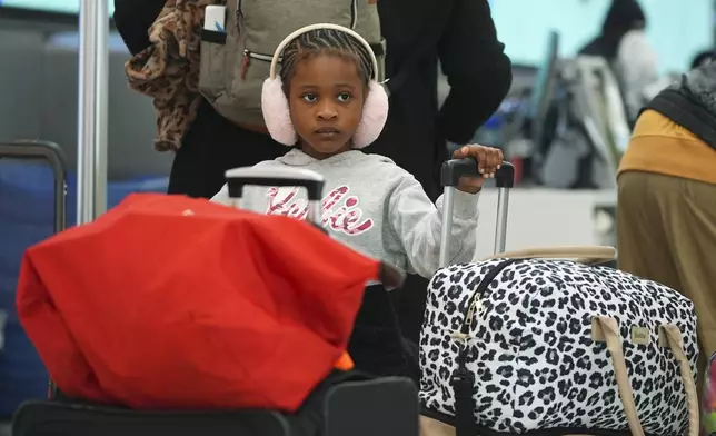 Young traveller queues up at a United Airlines self-check kiosk in Denver International Airport Tuesday, Dec. 24, 2024, in Denver. (AP Photo/David Zalubowski)