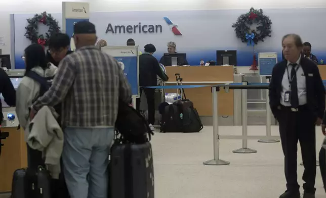 Passengers self-check baggage at the American Airlines terminal at George Bush Intercontinental Airport in Houston on Tuesday, Dec. 24, 2024, after American Airlines briefly grounded flights on Christmas Eve because of a technical problem. (AP Photo/Lekan Oyekanmi)