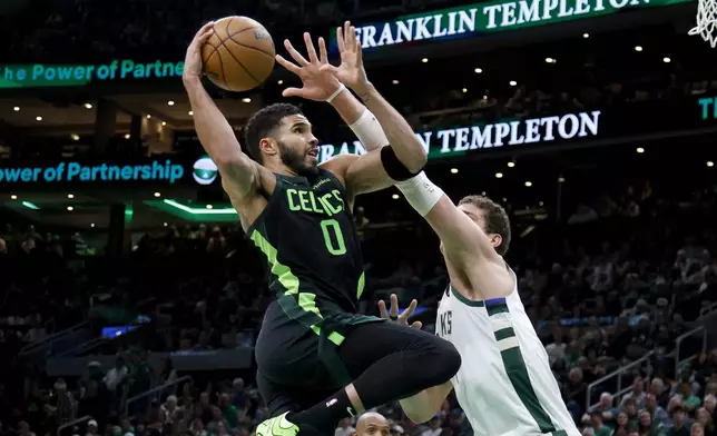 Boston Celtics forward Jayson Tatum (0) drives to the basket against Milwaukee Bucks center Brook Lopez (11) during the first half of an NBA basketball game, Friday, Dec. 6, 2024, in Boston. (AP Photo/Mary Schwalm)