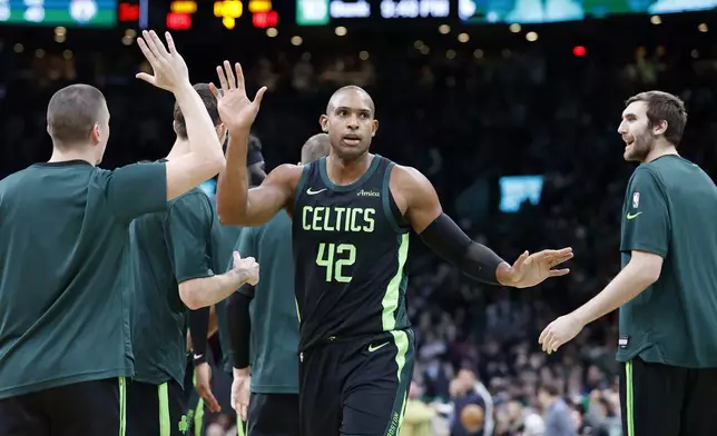 Boston Celtics center Al Horford (42) is congratulated by teammates after scoring late in the second half of an NBA basketball game against the Milwaukee Bucks, Friday, Dec. 6, 2024, in Boston. (AP Photo/Mary Schwalm)