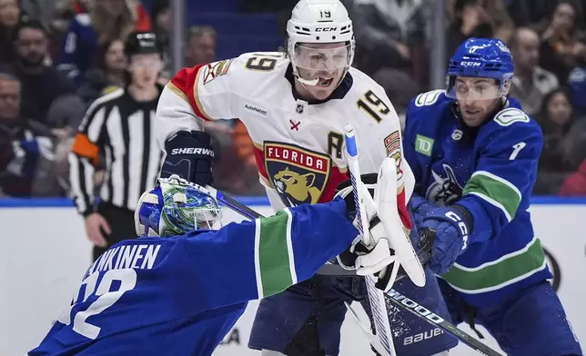 Vancouver Canucks goalie Kevin Lankinen (32) makes a blocker save as Carson Soucy (7) checks Florida Panthers' Matthew Tkachuk (19) during the second period of an NHL hockey game, Thursday, Dec. 12, 2024 in Vancouver, British Columbia. (Darryl Dyck/The Canadian Press via AP)