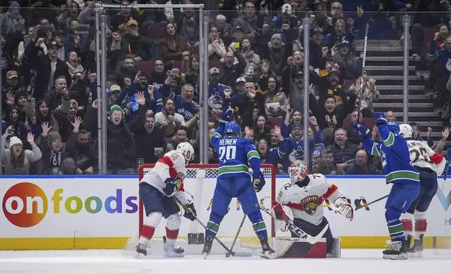 Vancouver Canucks' Danton Heinen (20) celebrates his goal against Florida Panthers goalie Sergei Bobrovsky (72) as Nate Schmidt, left, watches during the first period of an NHL hockey game, Thursday, Dec. 12, 2024 in Vancouver, British Columbia. (Darryl Dyck/The Canadian Press via AP)