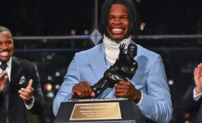 Colorado’s Travis Hunter holds the trophy after winning the Heisman Trophy as the outstanding player in college football, Saturday, Dec. 14, 2024, in New York. (Todd Van Emst/Heisman Trust via AP, Pool)