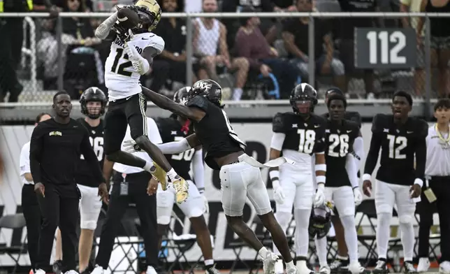 FILE - Colorado wide receiver Travis Hunter (12) catches a pass over Central Florida defensive back Brandon Adams (0) defends during the first half of an NCAA college football game, Saturday, Sept. 28, 2024, in Orlando, Fla. (AP Photo/Phelan M. Ebenhack, File)