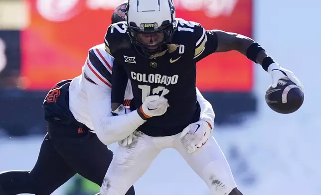 FILE- Colorado wide receiver Travis Hunter, front, is tackled after pulling in a pass by Oklahoma State safety Kobe Hylton in the first half of an NCAA college football game Friday, Nov. 29, 2024, in Boulder, Colo. (AP Photo/David Zalubowski, File)