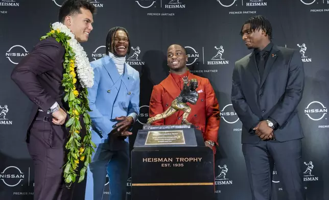 Heisman Trophy finalists, from left, Oregon's Dillon Gabriel, Colorado's Travis Hunter, Boise State's Ashton Jeanty and Miami's Cam Ward pose with the trophy during a college football press conference, Saturday, Dec. 14, 2024, in New York. (AP Photo/Corey Sipkin)