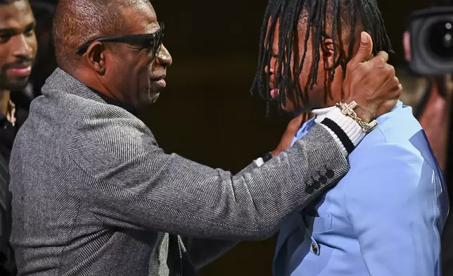 Colorado’s Travis Hunter, right, and coach Deion Sanders embrace after Hunter won the Heisman Trophy as the outstanding player in college football, Saturday, Dec. 14, 2024, in New York. (Todd Van Emst/Heisman Trust via AP, Pool)