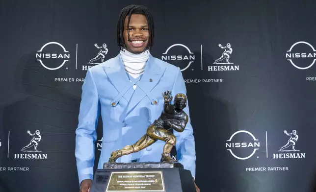 Heisman Trophy finalist Travis Hunter, of Colorado, stands with the trophy during a college football press conference, Saturday, Dec. 14, 2024, in New York. (AP Photo/Corey Sipkin)