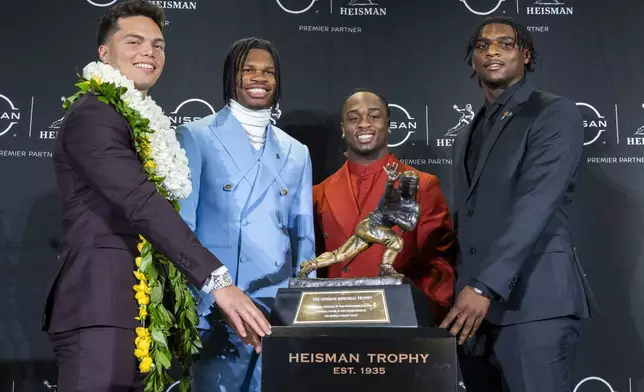 Heisman Trophy finalists, from left, Oregon's Dillon Gabriel, Colorado's Travis Hunter, Boise State's Ashton Jeanty and Miami's Cam Ward pose with the trophy during a college football press conference, Saturday, Dec. 14, 2024, in New York. (AP Photo/Corey Sipkin)