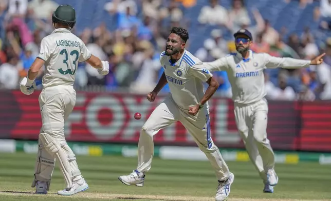 India's Mohammed Siraj, center, and Virat Kohli, right, celebrates the wicket of Australia's Marnus Labuschagne, left, during play on the day four of the fourth cricket test between Australia and India at the Melbourne Cricket Ground, Melbourne, Australia, Sunday, Dec. 29, 2024. (AP Photo/Asanka Brendon Ratnayake)