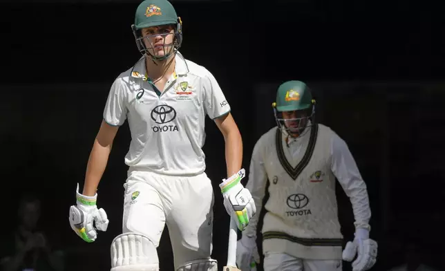 Australia's Sam Konstas, left, and Usman Khawaja walk out to bat during play on the day four of the fourth cricket test between Australia and India at the Melbourne Cricket Ground, Melbourne, Australia, Sunday, Dec. 29, 2024. (AP Photo/Asanka Brendon Ratnayake)