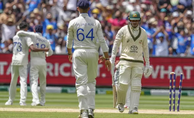 Australia's Usman Khawaja, right, walks off the field as Indian players celebrate his wicket during play on the day four of the fourth cricket test between Australia and India at the Melbourne Cricket Ground, Melbourne, Australia, Sunday, Dec. 29, 2024. (AP Photo/Asanka Brendon Ratnayake)