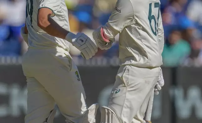 Australia's Nathan Lyon, right, fist bumps with batting partner Scott Boland during play on the day four of the fourth cricket test between Australia and India at the Melbourne Cricket Ground, Melbourne, Australia, Sunday, Dec. 29, 2024. (AP Photo/Asanka Brendon Ratnayake)