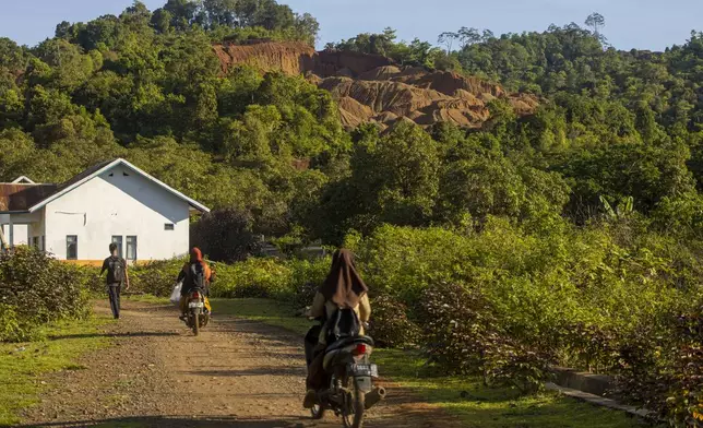 Students head to school as a hill that has been mined for nickel ore is visible in the background on Kabaena Island in South Sulawesi, Indonesia, Saturday, Nov. 16, 2024,. (AP Photo/Yusuf Wahil)