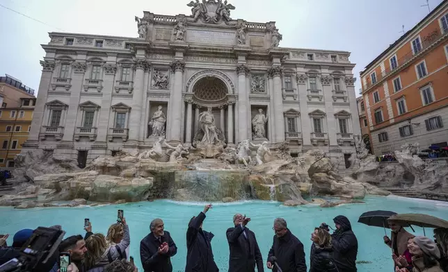 FILE - Rome's mayor Roberto Gualtieri, center, tosses a coin into the 18th century Trevi Fountain, one of Rome's most iconic landmarks, as it reopens to the public after undergoing maintenance, just on time for the start of the Jubilee Year, an event expected to draw millions of visitors to the Eternal City, in Rome, Sunday, Dec. 22, 2024. (AP Photo/Andrew Medichini, File)