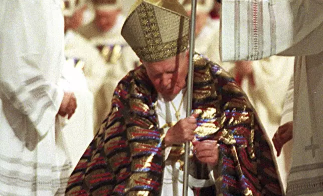 FILE - Pope John Paul II walks through the bronze Holy Door of St. Peter's Basilica at the Vatican, late Friday night, Dec. 24, 1999. (AP Photo/Andrew Medichini, File)