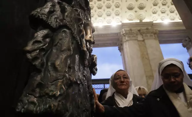 FILE - Nuns reach out to touch the the Holy Door of the St. John in Lateran basilica in Rome, Sunday, Nov. 13, 2016. (AP Photo/Gregorio Borgia, File)