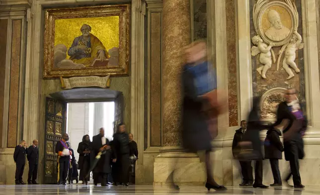 FILE - In this photo taken with a slow shutter speed, people walk through the Holy Door of St. Peter's Basilica, at the Vatican, Tuesday, Dec. 8, 2015. (AP Photo/Andrew Medichini, File)