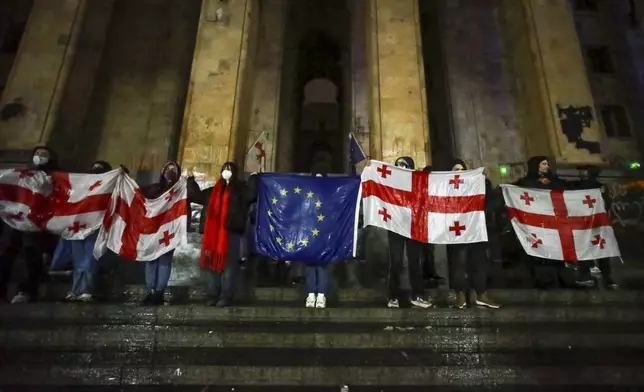 Protesters hold an EU and Georgian national flags during a rally against the governments' decision to suspend negotiations on joining the European Union for four years, outside the parliament's building in Tbilisi, Georgia, on Sunday, Dec. 1, 2024. (AP Photo/Zurab Tsertsvadze)