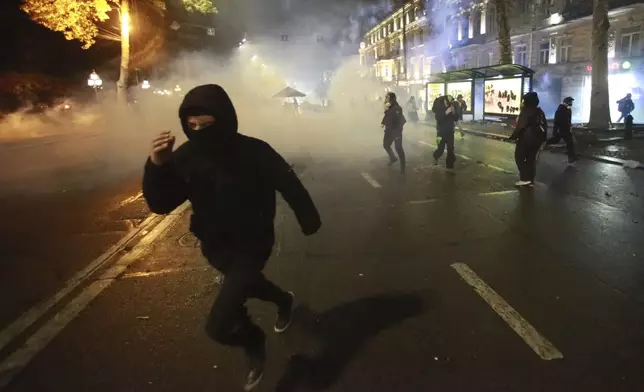 Demonstrators run away from a cloud of tear gas during a rally against the government's decision to suspend negotiations on joining the European Union for four years in Tbilisi, Georgia, Monday, Dec. 2, 2024. (AP Photo/Zurab Tsertsvadze)