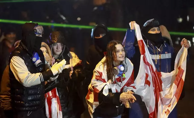 Protesters with Georgian national flags shout toward police during a rally against the governments' decision to suspend negotiations on joining the European Union for four years, outside the parliament's building in Tbilisi, Georgia, on Sunday, Dec. 1, 2024. (AP Photo/Zurab Tsertsvadze)