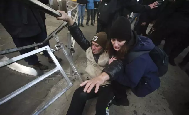 A woman helps a demonstrator up at a subway station during a rally against the government's decision to suspend negotiations on joining the European Union for four years in Tbilisi, Georgia, Monday, Dec. 2, 2024. (AP Photo/Zurab Tsertsvadze)