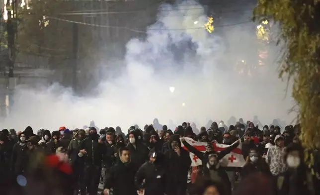 Demonstrators run away from a cloud of tear gas during a rally against the government's decision to suspend negotiations on joining the European Union for four years in Tbilisi, Georgia, Monday, Dec. 2, 2024. (AP Photo/Zurab Tsertsvadze)