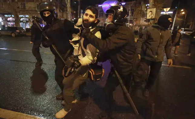 Police officers detain journalist Giorgi Chamelishvili during a rally against the government's decision to suspend negotiations on joining the European Union for four years, outside the parliament's building in Tbilisi, Georgia, early Monday, Dec. 2, 2024. (AP Photo/Zurab Tsertsvadze)