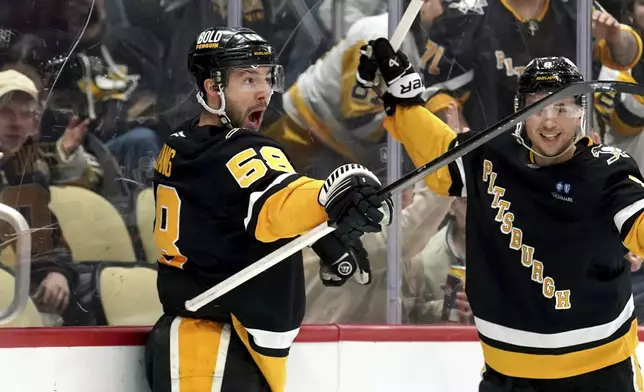 Pittsburgh Penguins' Kris Letang (58) celebrates with Michael Bunting, right, after scoring during the second period of an NHL hockey game against the Florida Panthers Tuesday, Dec. 3, 2024, in Pittsburgh. (AP Photo/Matt Freed)